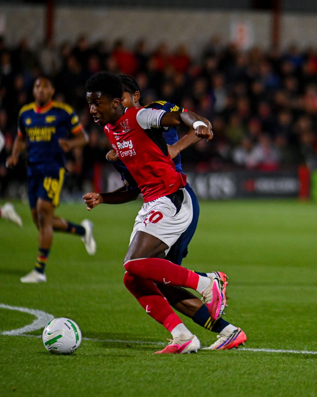 Aaron Loupalo-Bi, on loan from Fulham, holds off his man in Fleetwood red on Tuesday night. Loupalo-Bi outmuscled Marli Salmon and finished past Illan Meslier to put the League Two side in front in the 21st minute.