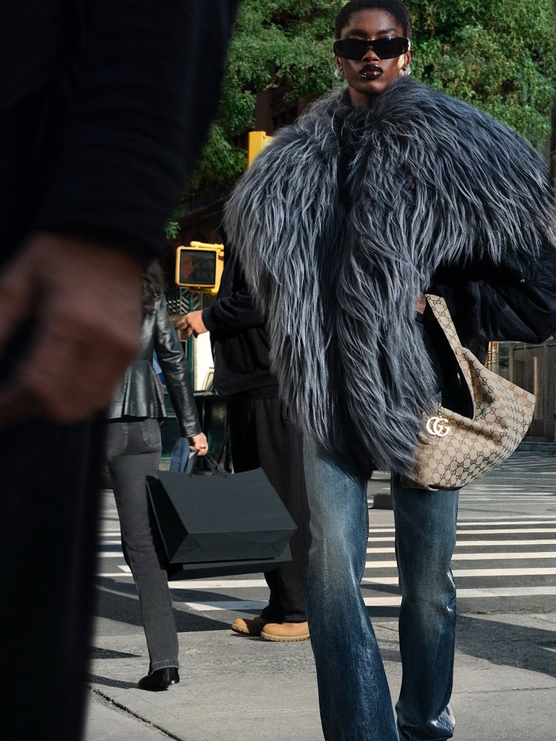 A Gucci look on a New York street, monogram bag in hand, from the brand's GucciCore campaign. The product is visible. The shoppers, Kering says, are not walking in.
