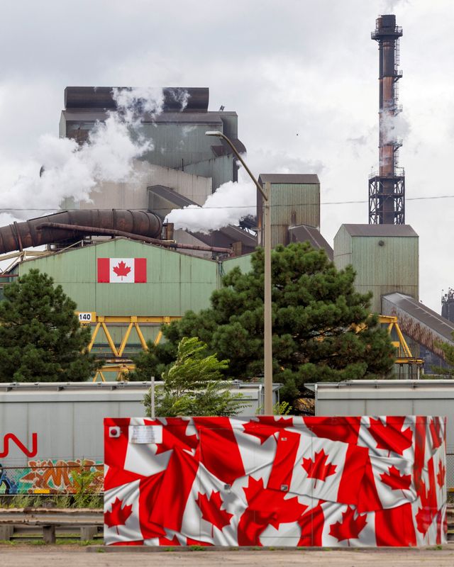 A Canadian steel mill flying Canadian flags, in the Reuters photograph carried with the report. Steel is one of the two industries at the centre of the tariff talks.